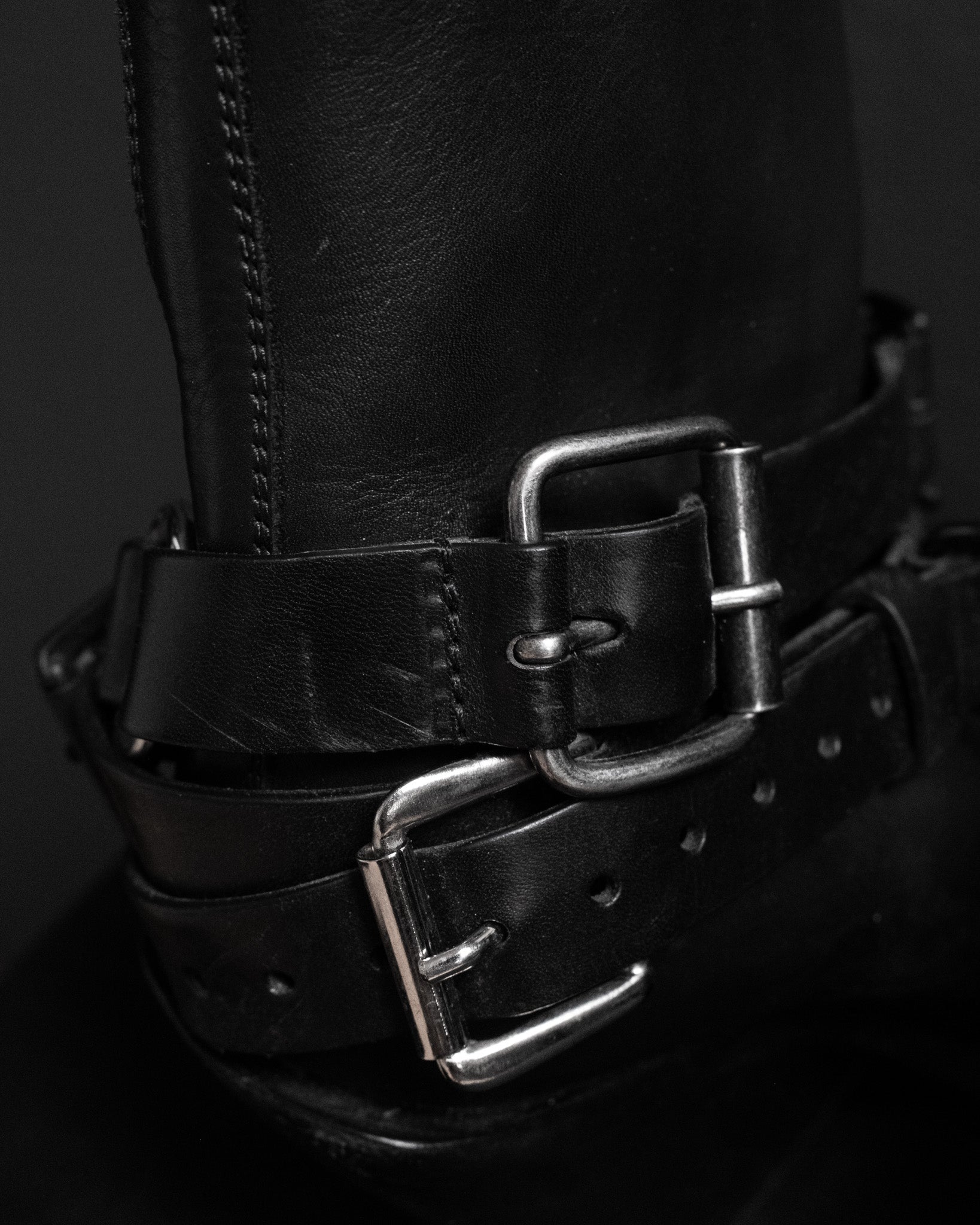 Ann Demeulemeester black leather belt buckle boots. Close up view on buckles.
